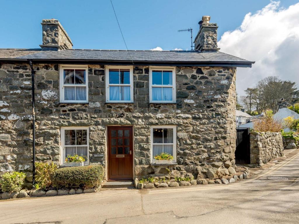 a stone house with a red door on a street at 2 Bed in Aberdovey 80399 in Llwyngwril