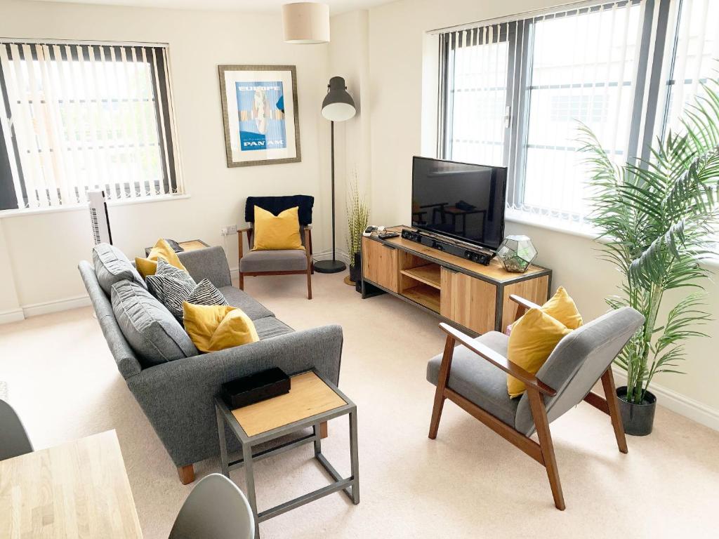a living room with a couch and a tv at Travaal.©om - 2 Bed Serviced Apartment Farnborough in Farnborough