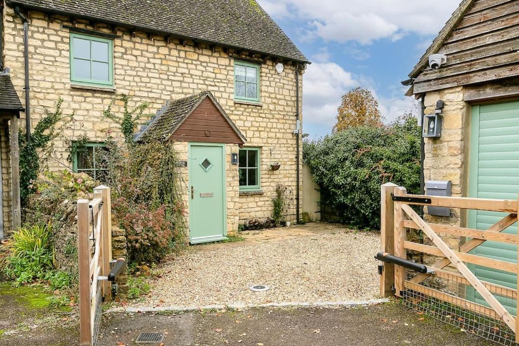 ein Backsteinhaus mit grüner Tür und Tor in der Unterkunft Stunning 3BD Oxfordshire Cottage in Enstone in Enstone