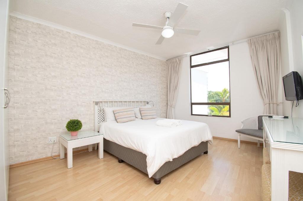 a white bedroom with a bed and a window at 423 Breakers Resort in Durban