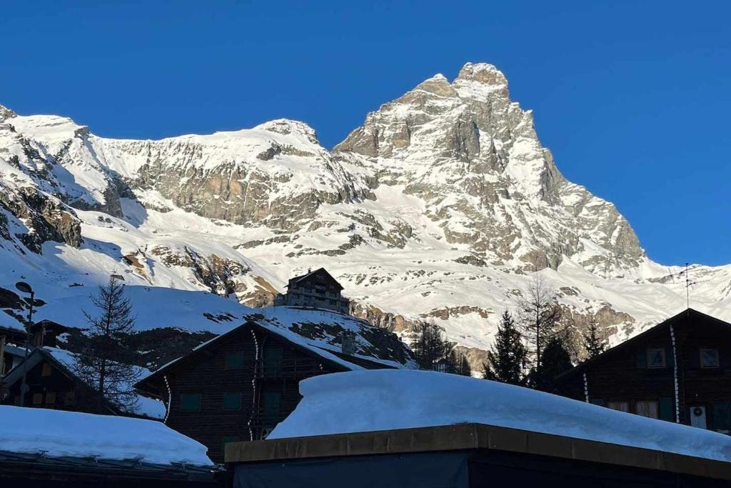 een met sneeuw bedekte berg met huizen ervoor bij Casa a Cervinia sulle piste in Breuil-Cervinia