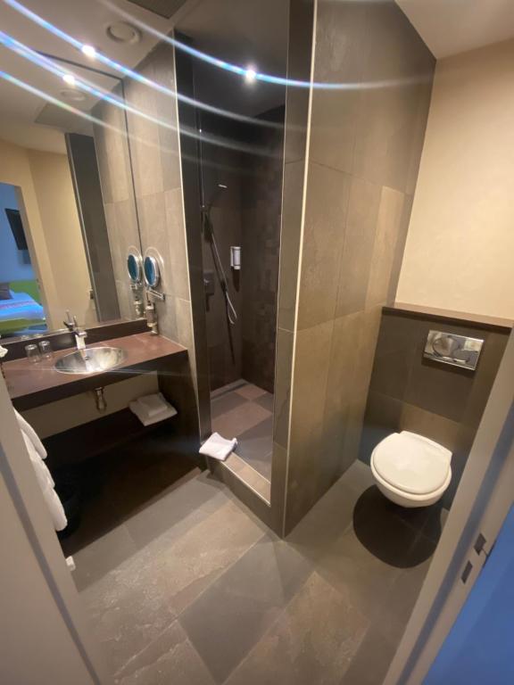 a bathroom with a shower and a toilet and a sink at Hotel Des Lices in Rennes