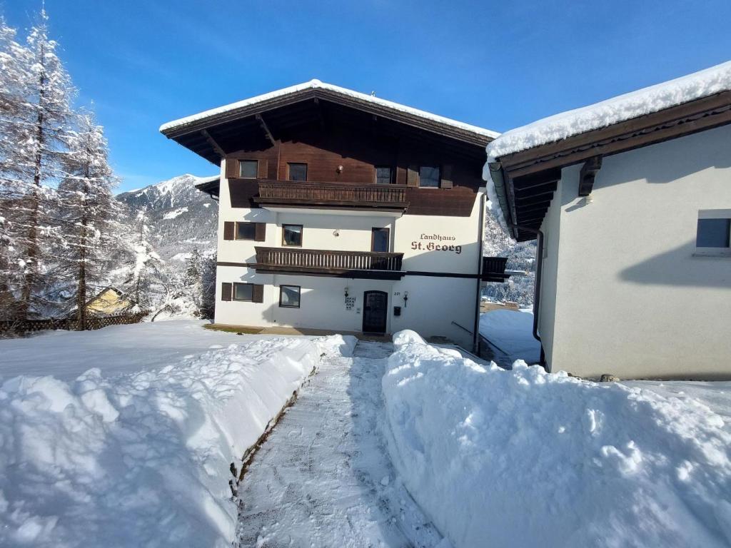 een gebouw bedekt met sneeuw naast een sneeuwbedekte oprit bij Apartment Landhaus St- Georg-7 by Interhome in Bad Gastein