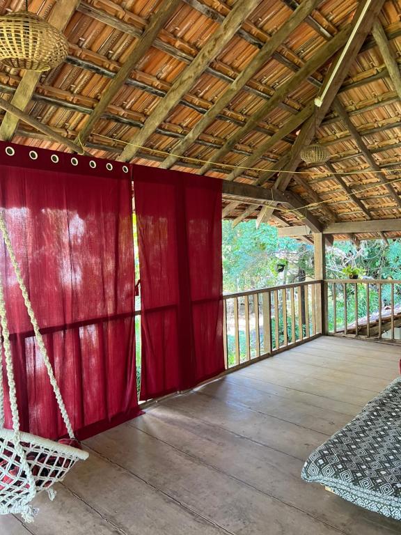 a screened porch with red curtains and a hammock at The Sunset Chalet! in Anjuna