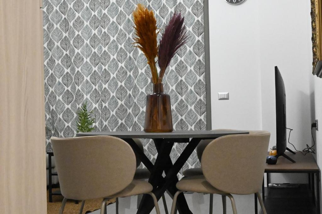 een eettafel met stoelen en een vaas met veren bij Casa karas in Milaan