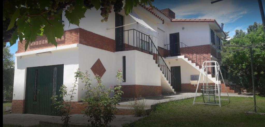 una casa blanca con una escalera delante en Departamentos Posada de los angeles en Capilla del Monte