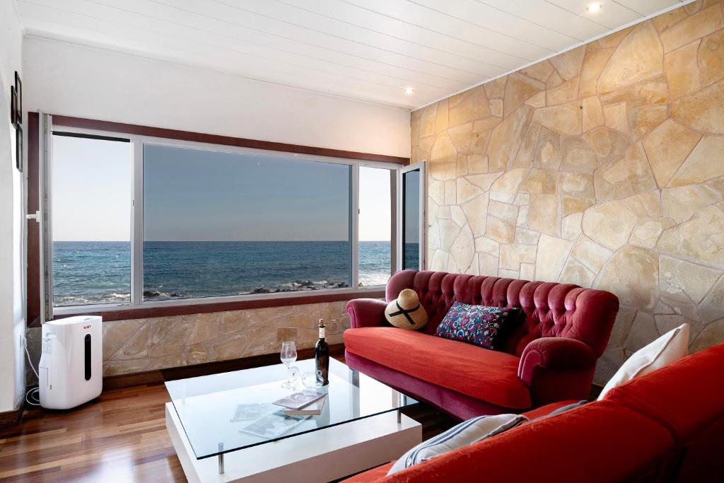 sala de estar con sofá rojo y ventana grande en El Mar y Tú, en Arrieta