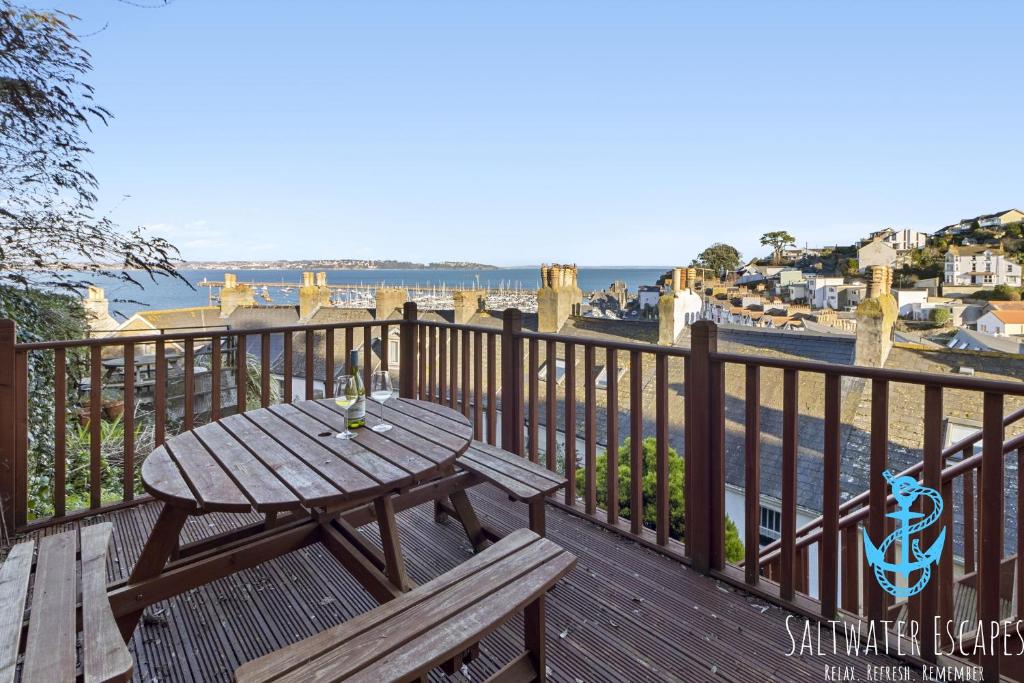 a wooden table and bench on a balcony with a view of the water at Coastal View Cottage in Torquay