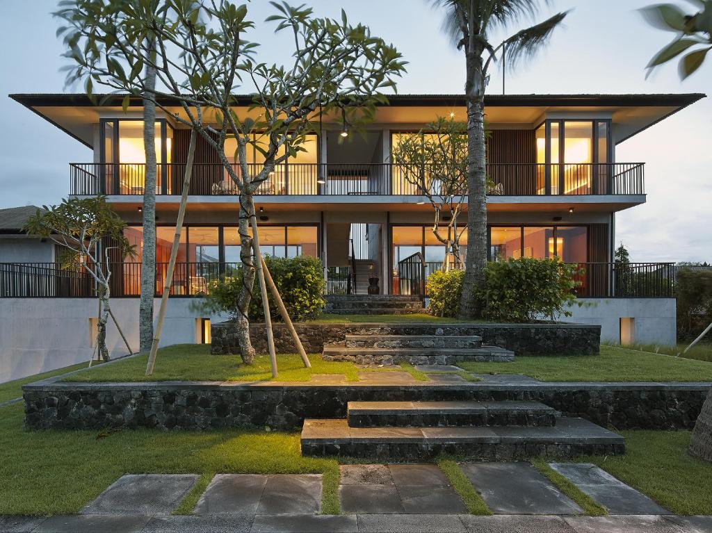 a house with a lot of windows and trees at Arnalaya Beach House in Canggu