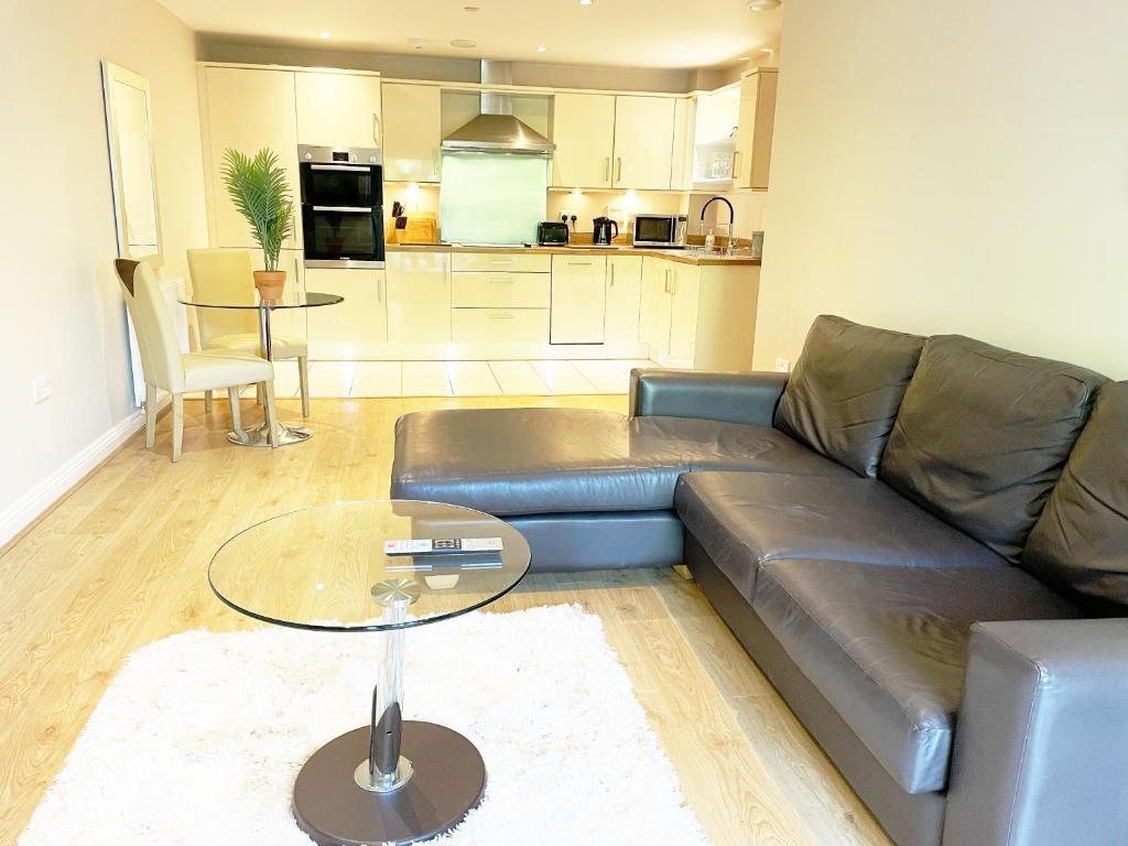Travaal.©om - 2 Bed Apartment Farnborough في فارنبورو: غرفة معيشة مع أريكة جلدية وطاولة زجاجية