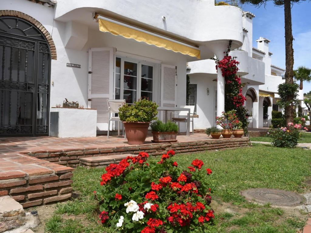 una casa blanca con flores rojas en el patio en 59 Beautiful Mijas Playa Club en La Cala de Mijas