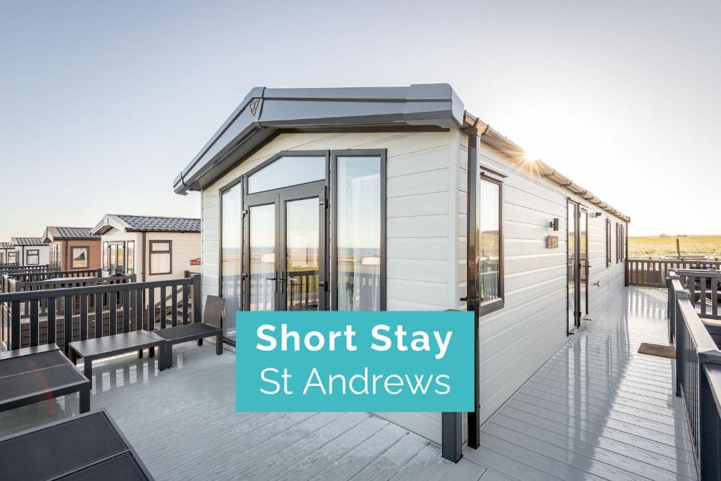 a tiny house on a deck with benches at Lodge No 9 - St Andrews Lodge Park in Strathkinness
