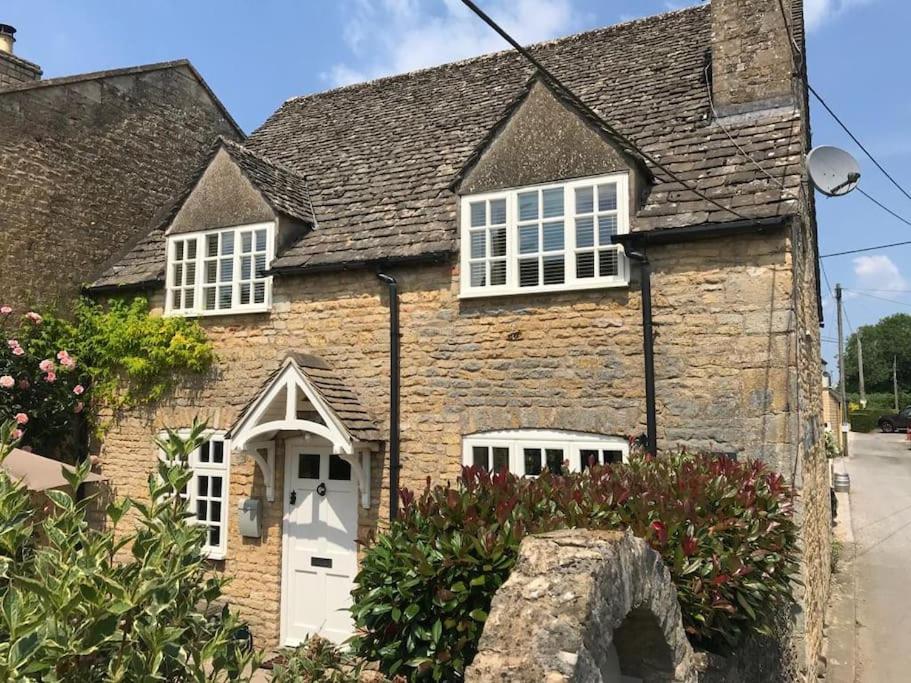 a stone house with a white door and windows at Jasmine Cottage - 2 Bedroom in Heart of Bourton! in Bourton on the Water