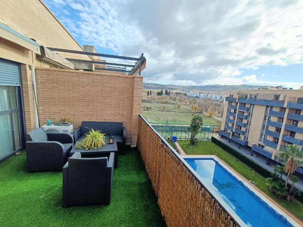 balcón con muebles de exterior y piscina en Acogedora habitación privada en Villa Mayka en Granada