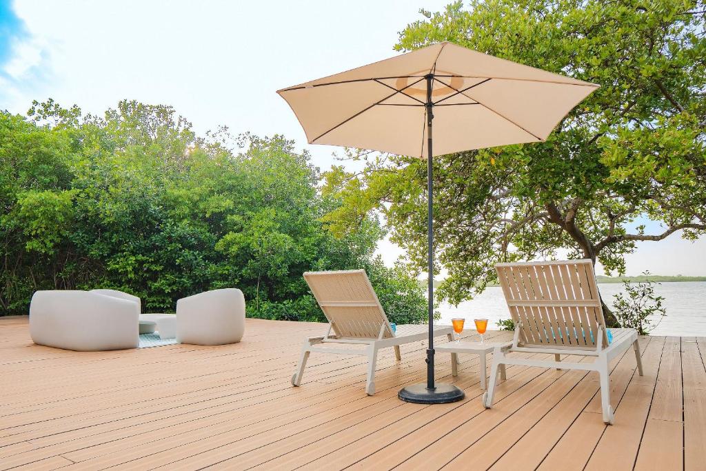two chairs and a table with an umbrella on a deck at U-GO Espectacular Casa en Barú con Vistas al Mar in Cartagena de Indias