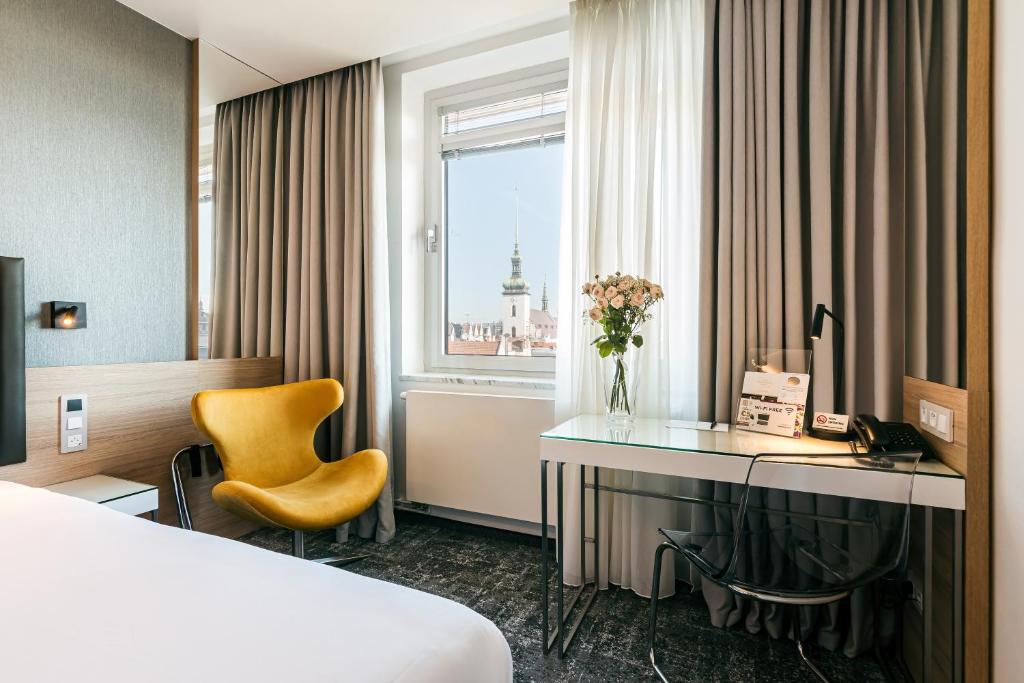 a hotel room with a bed and a desk and a window at Hotel International Brno in Brno