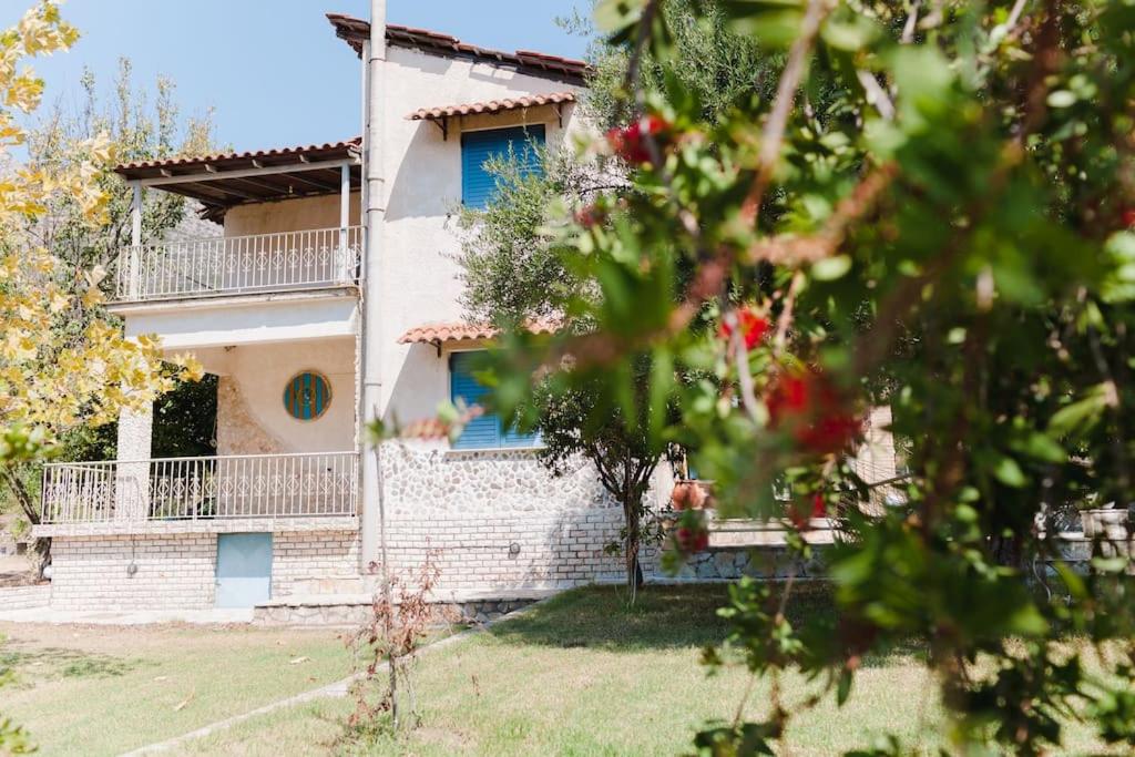 uma casa com janelas azuis e um quintal em Casa di campagna em Faskomiliá