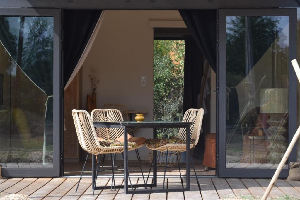 a table and chairs on a patio with glass doors at La cabane in Beaurepaire