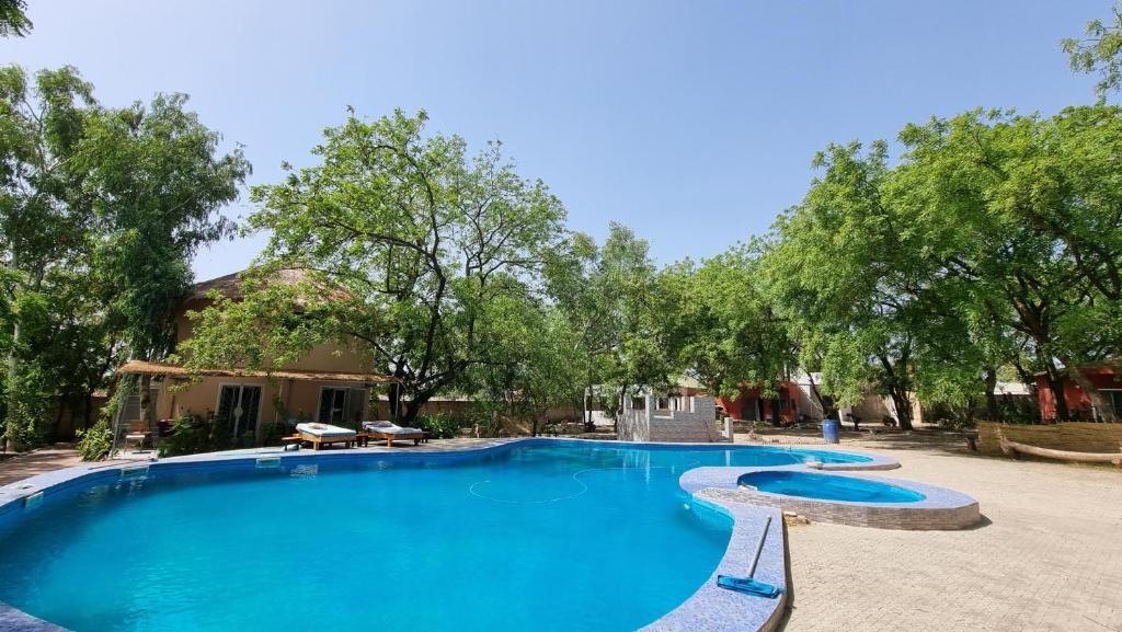 een groot blauw zwembad met bomen op de achtergrond bij Les Fromagers in Missira