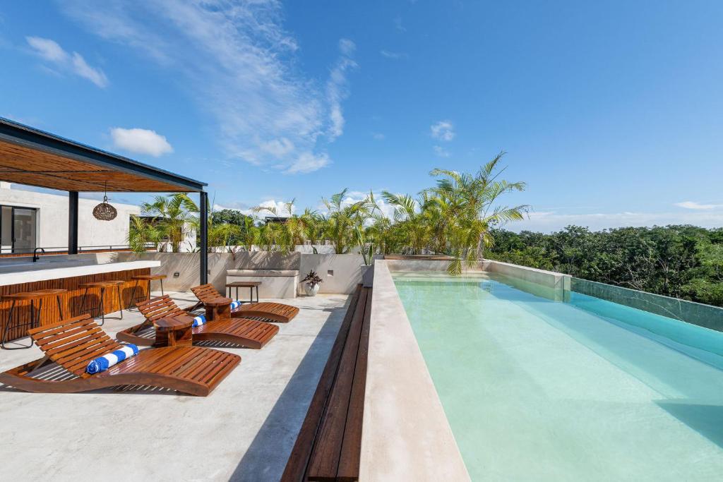 a swimming pool with chaise lounges and chairs next to a house at Irie Tulum in Tulum