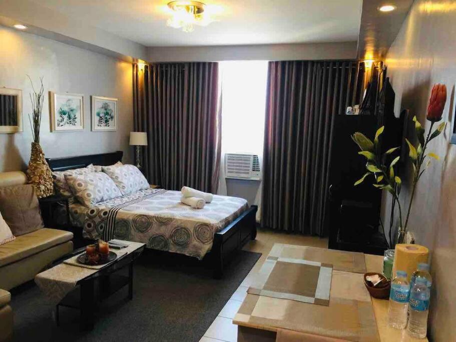 ein Wohnzimmer mit einem Bett und einem Sofa in der Unterkunft Yulee’s Comfortable Home Seakyung Village condo in Lapu Lapu City