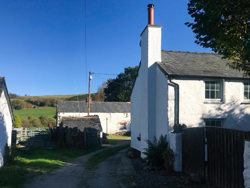 a small white house with a fence next to a road at Swallow Cottage - A Cosy Retreat Near Snowdonia and the Coast in Abergele