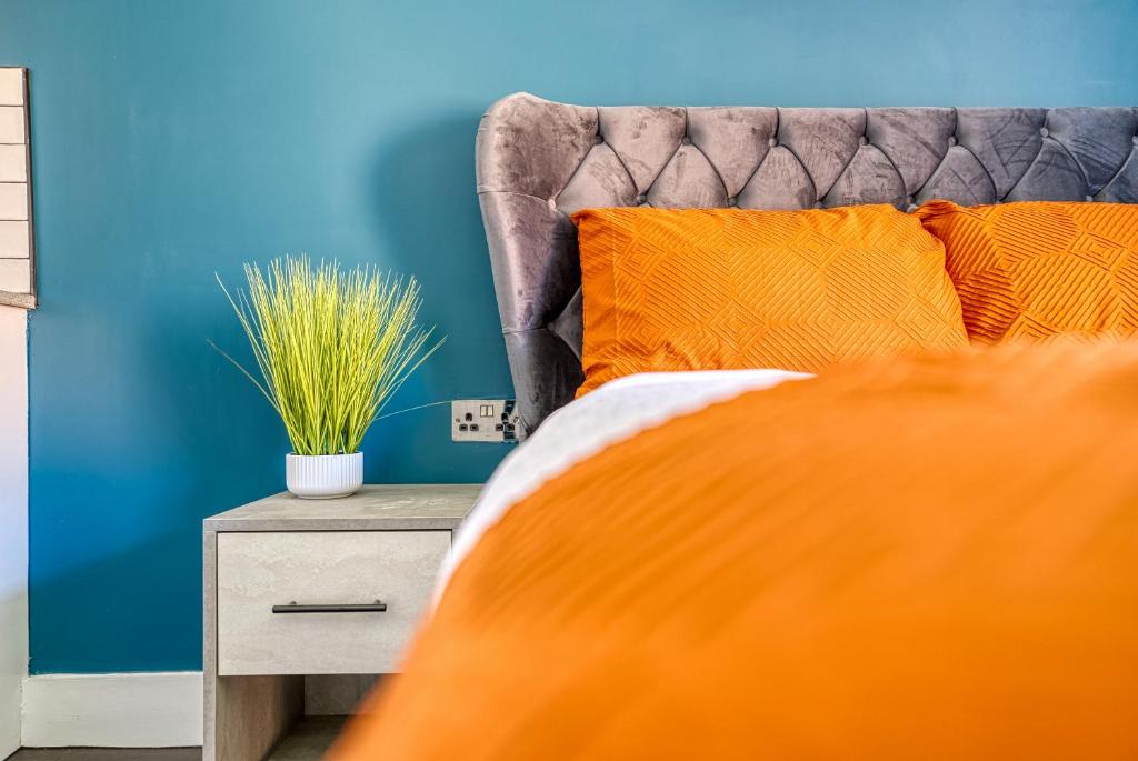 een bed met oranje kussens en een blauwe muur bij Private Ensuite Rooms Coventry in Walsgrave on Sowe