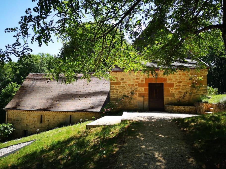 een bakstenen gebouw met een deur in een veld bij Maison climatisée avec jacuzzi à 10 min de Sarlat in Sarlat-la-Canéda