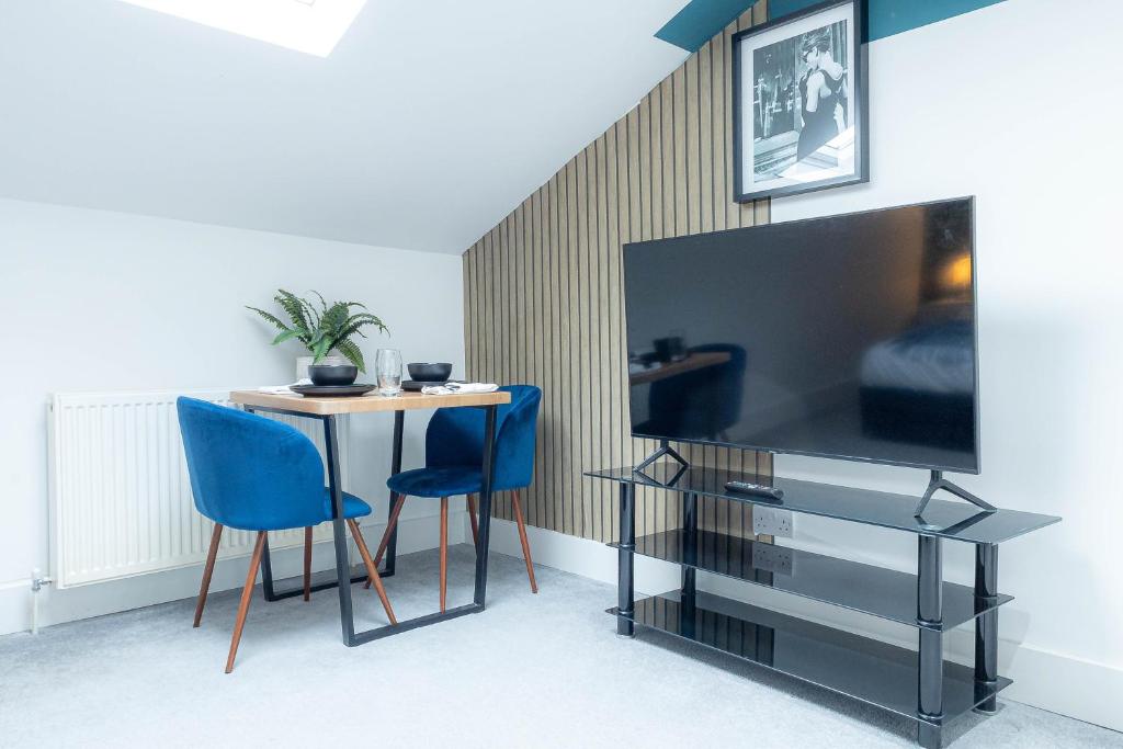 a room with a table and blue chairs and a tv at Deluxe Urban Retreat with City Views Studio and One Bedroom Apartments near Camden by Belvilla in London