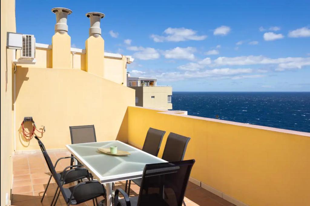 una mesa y sillas en un balcón con vistas al océano en Sunlivetenerife, en Candelaria