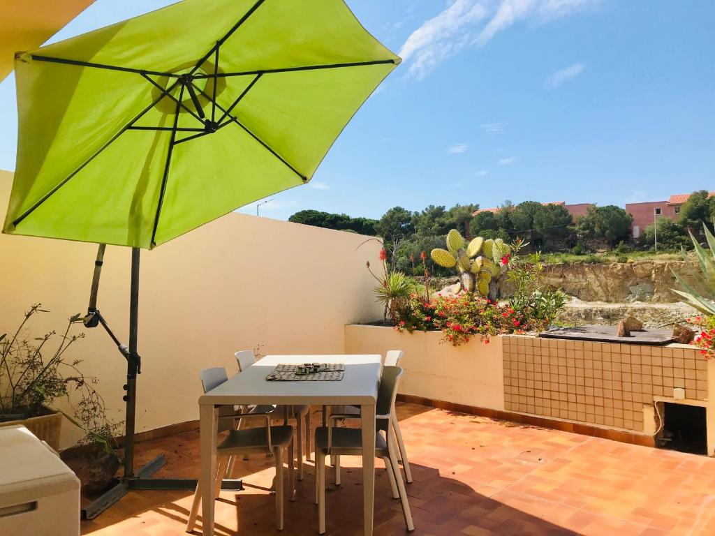 - un parasol vert sur une terrasse avec une table et des chaises dans l'établissement Appartement PORTO 35 Lumio, à Lumio