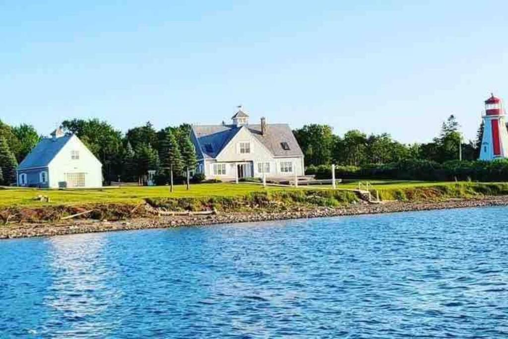 een huis en een vuurtoren naast een waterlichaam bij Sea Cliff Cottage in Edwardsville