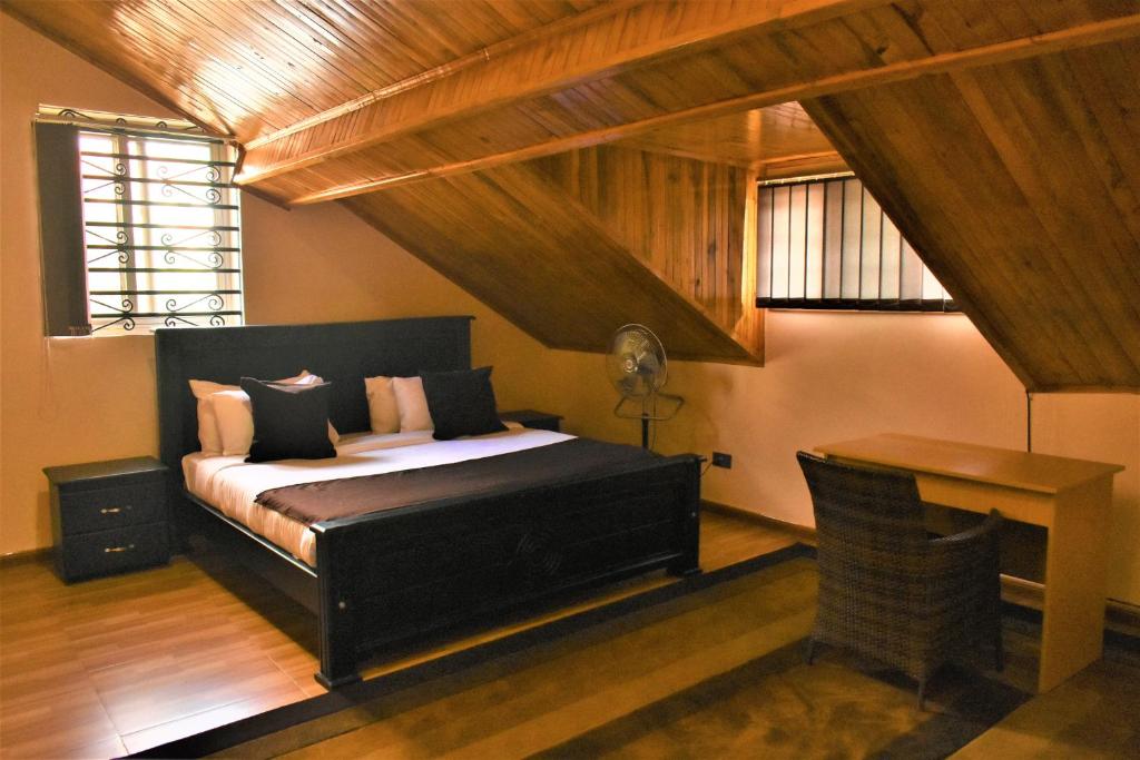 a bedroom with a bed and a desk and a window at Ezeife Guesthouse in Kampala