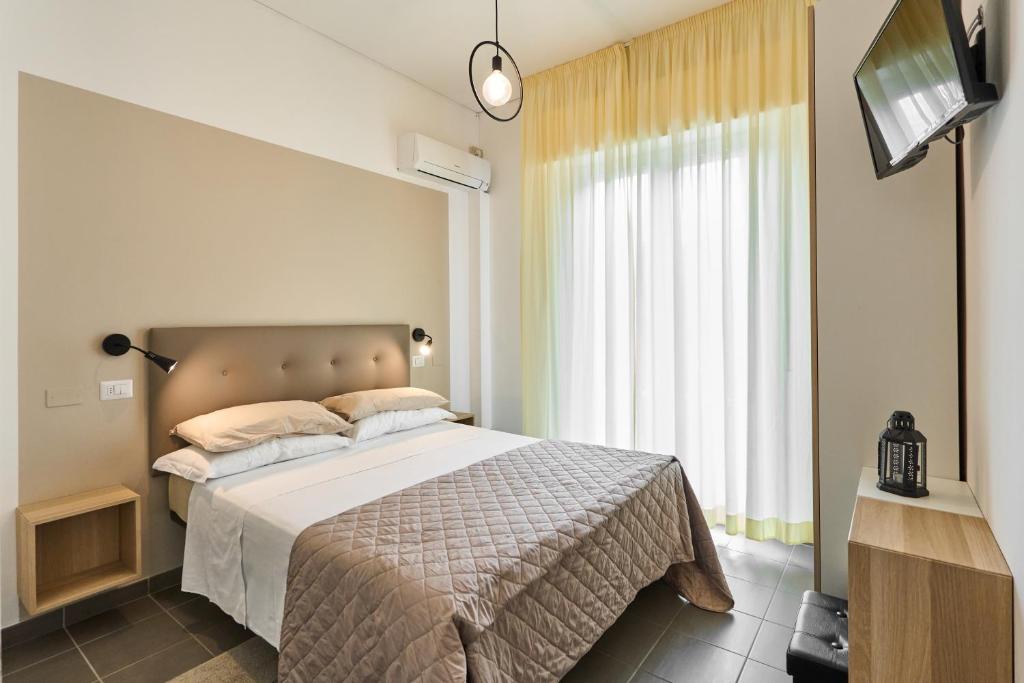 een slaapkamer met een groot bed en een televisie bij Hotel Villa Perazzini in Rimini