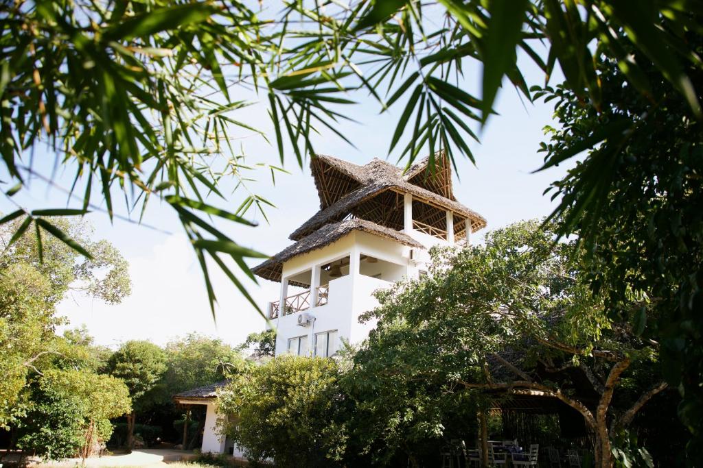 un edificio blanco con techo sobre árboles en Watamu Beach Cottages B&B en Watamu