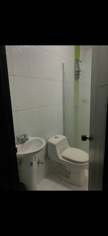 La salle de bains blanche est pourvue de toilettes et d'un lavabo. dans l'établissement Edificio owen, à Barranquilla