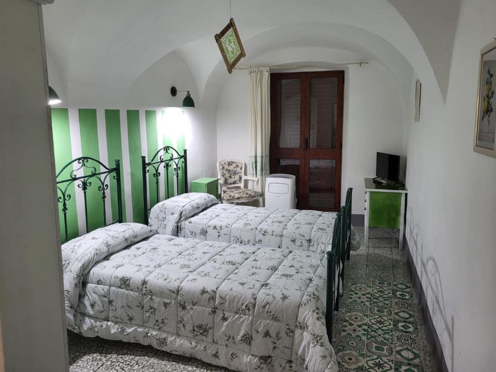 - 2 lits dans une chambre à rayures vertes et blanches dans l'établissement Casa Eleonora, à Bosa