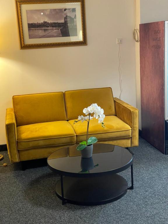 sala de estar con sofá amarillo y mesa en Hotel Oáza Praha en Praga