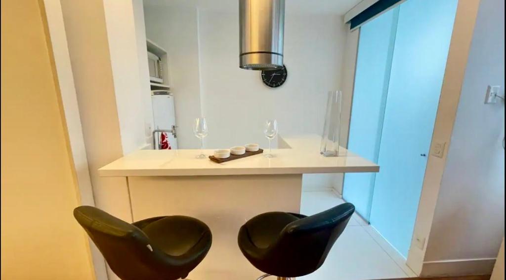 una cocina con 2 sillas negras y una mesa en Apartamento Studio Arpex HIR 25, en Río de Janeiro