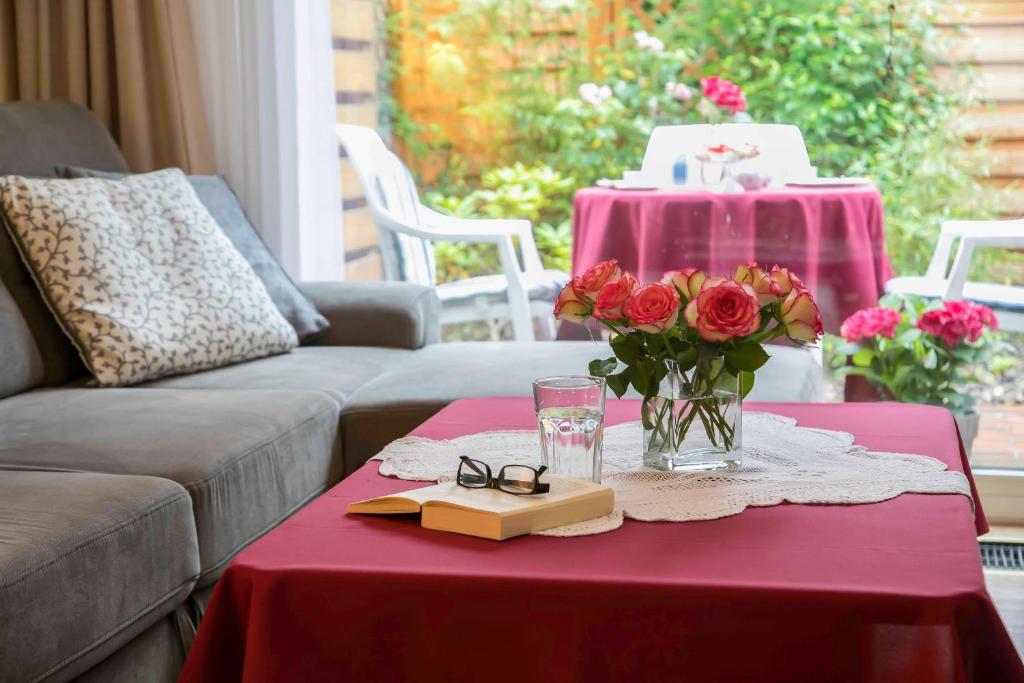 a table with a vase of roses and glasses on it at Ferienhaus an der Baeke E in Bad Zwischenahn