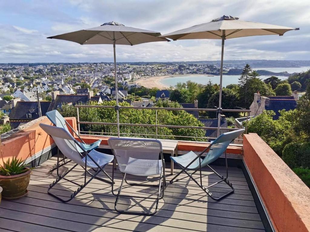 d'une terrasse sur le toit avec des chaises et des parasols. dans l'établissement 661 - Charmante maison en pierre sur les Hauteurs d'Erquy avec vue mer, à Erquy