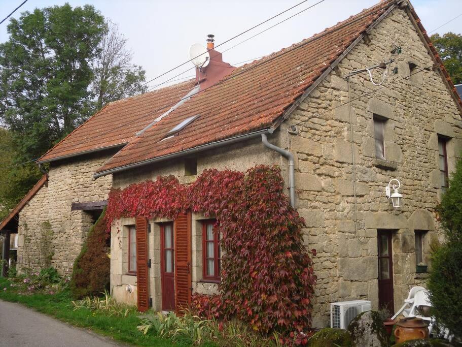 une maison en pierre avec du lierre rouge dans l'établissement Gîte d'Alexandre, à Savennes