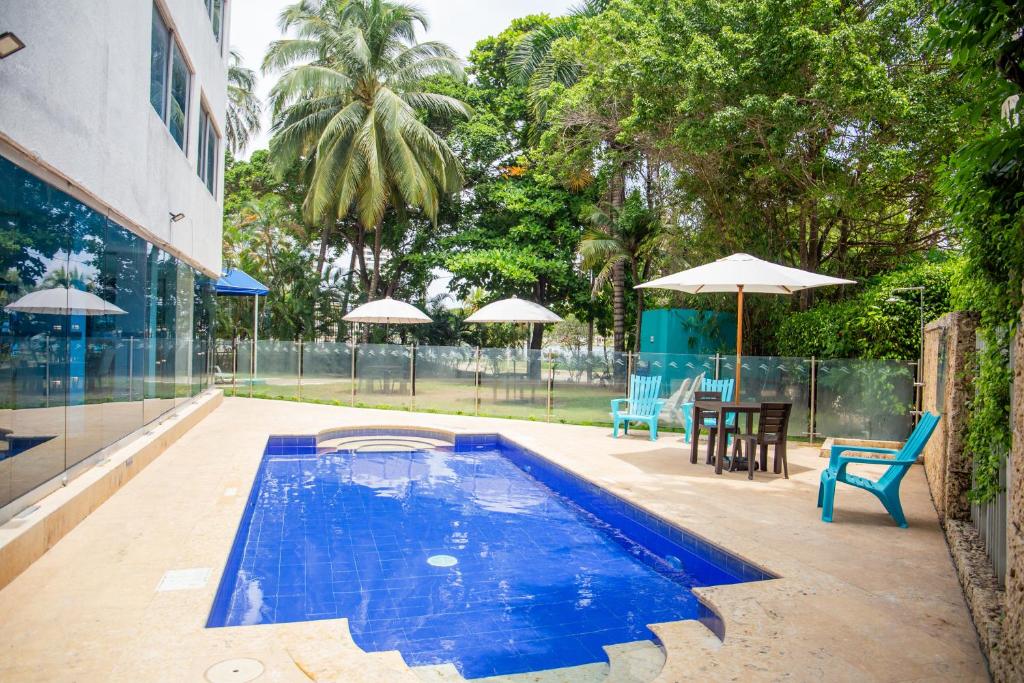 卡塔赫納的住宿－HOTEL OCEANIA，一个带椅子、桌子和遮阳伞的游泳池