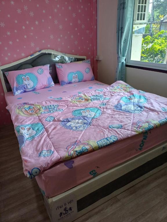 a bed with a pink comforter and pillows at ละเมอ เกสเฮ้าส์ บางแสน ซอย1 in Ban Bang Saen (1)