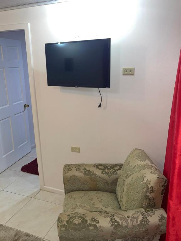 a room with a chair and a television on a wall at KSA Apartments in Georgetown