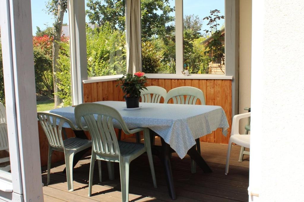 - une table et des chaises sur une terrasse couverte avec fenêtres dans l'établissement 602 - A ERQUY, jolie maison avec un grand jardin de 700m2 proche des plages sauvages, à Erquy