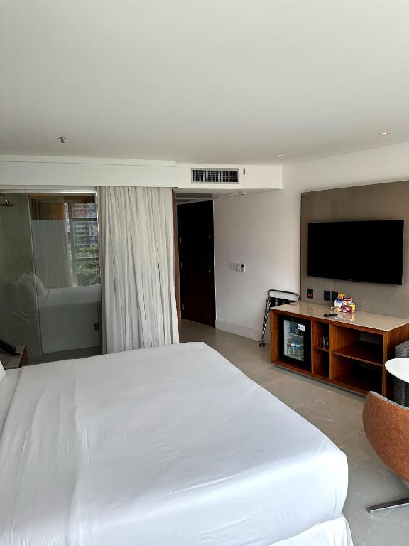 1 dormitorio con 1 cama blanca grande y TV de pantalla plana en Hotel Nacional RJ apto 504, en Río de Janeiro