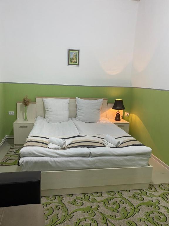 1 dormitorio con cama blanca y pared verde en Lind Hotel and Guest House, en Gyumri