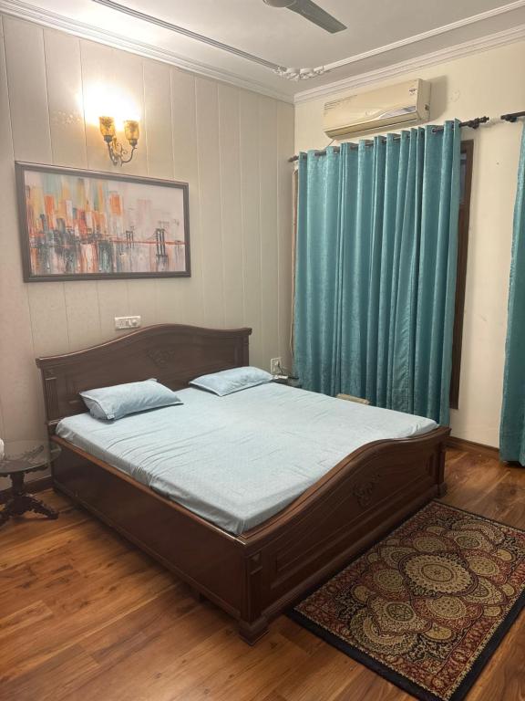 a bedroom with a large bed with blue curtains at Singh villa in Mohali