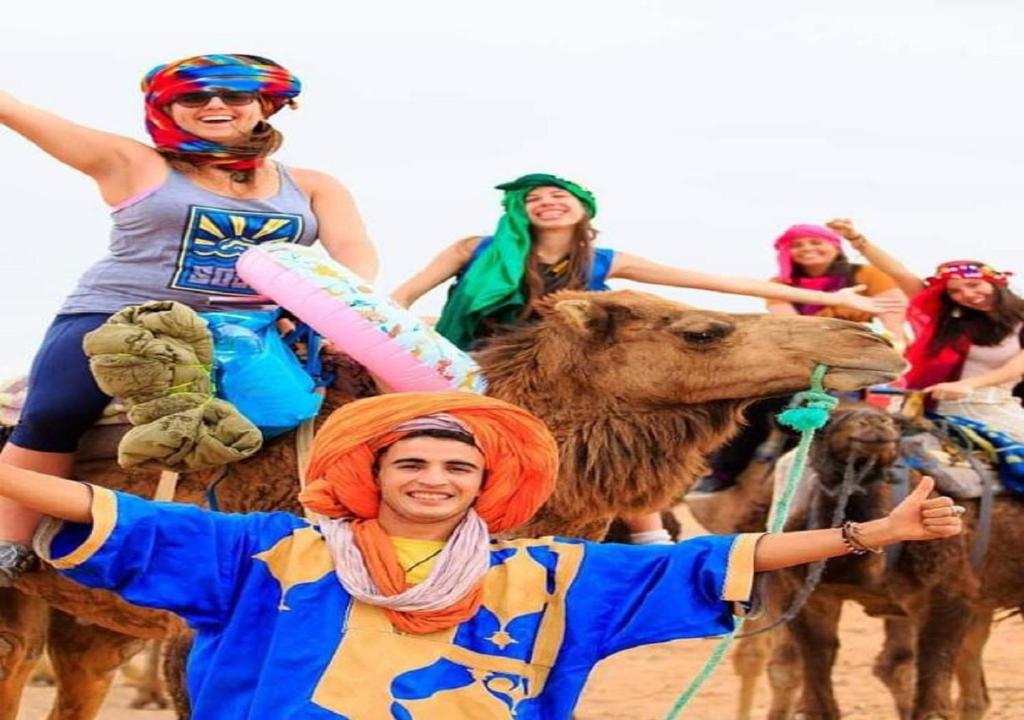 a group of people riding on the backs of a camel at Camel trekkings in Adrouine